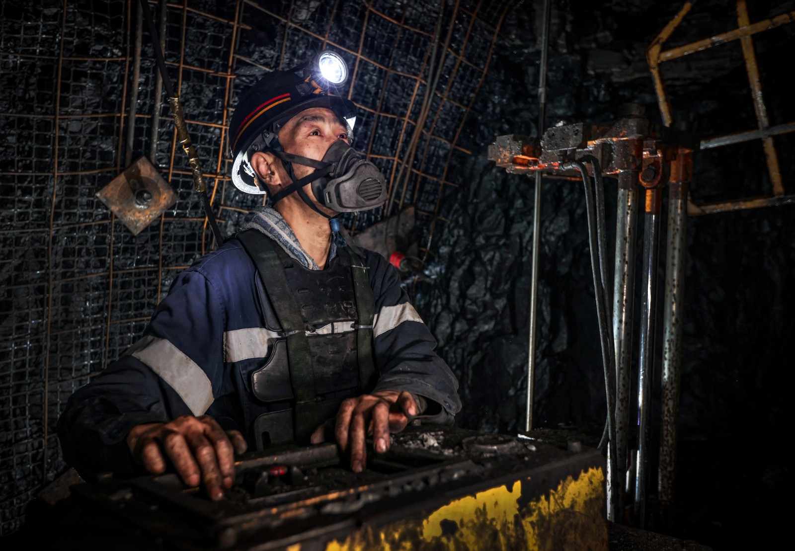 班组职工操作锚杆钻机对巷道顶板进行支护作业。