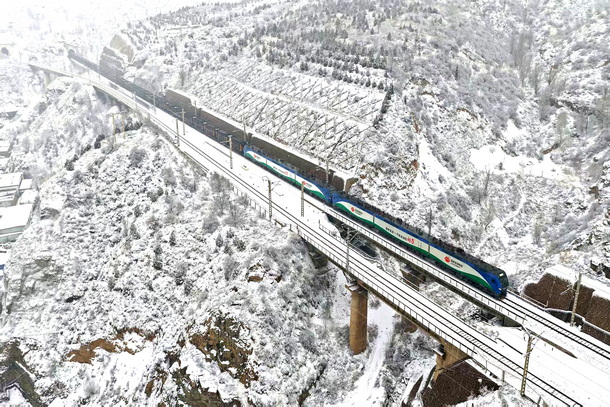 图为神朔铁路万吨重载列车行驶在风雪漫天的高架桥上